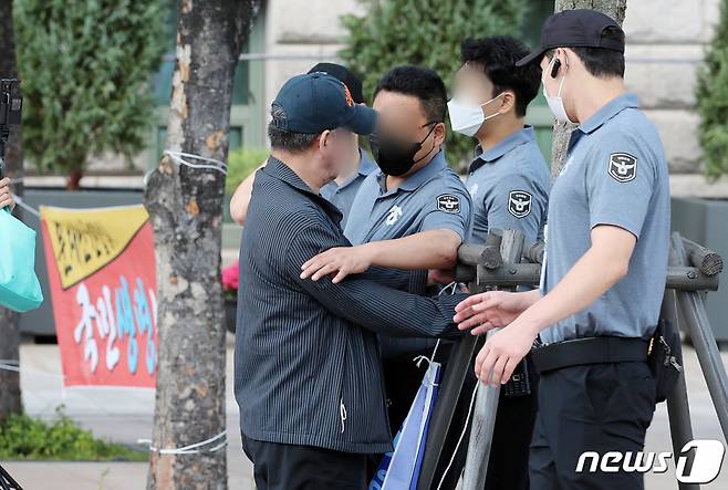 한 보수단체 회원이 지난 8일 오후 3시쯤 서울광장 앞에서 1인 현수막 시위를 펼치는 중 청원경찰을 밀치고 있다./사진=뉴스1