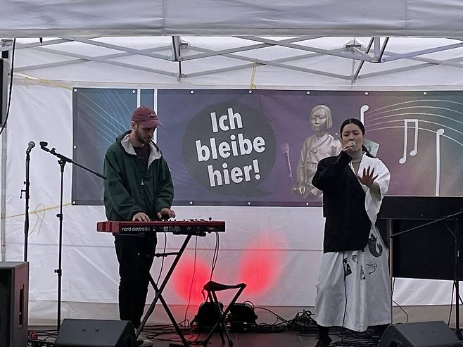 (베를린=연합뉴스) 이 율 특파원 = 18일(현지시간) 시민단체 코리아협의회가 베를린 평화의 소녀상 설치 1주년을 기념해 연 콘서트 겸 영구설치 촉구집회에서 싱어송라이터 멀레이의 공연. 2021.9.18