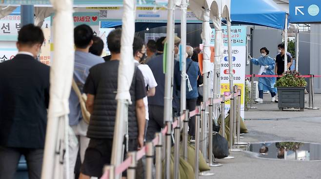 신종 코로나바이러스 감염증(코로나19) 신규 확진자 수가 1605명을 기록한 20일 오전 서울역 코로나19 선별진료소을 찾은 시민들이 검사를 기다리고 있다. [연합]