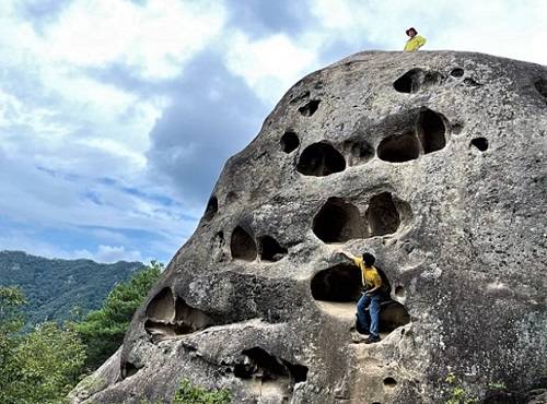 해골바위는 눈, 코, 입 모양이 확연히 보인다. 한 탐방객은 입에 올라 타 콧구멍을 바라보고 있다. 머리 위에 오른 다른 관광객은 풍경을 감상하고 있다.
