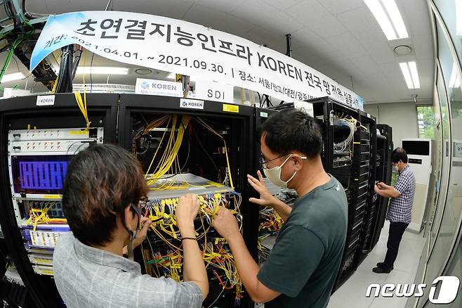 ETRI 연구진이 국가연구개발망(KOREN)에 데이터 중심 네트워킹 실증 케이블 연결상태를 점검하고 있는 모습. 왼쪽부터 이종석 연구원, 신용윤 연구원. (ETRI 제공) © 뉴스1