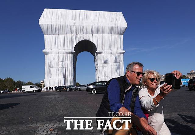건축물과 자연, 오브제 등을 거대한 천으로 포장하는 작업으로 거장 반열에 오른 대지 미술가 고(故) 크리스토 자바체프(Christo Javacheff)와 잔 클로드(Jeanne-Claude) 부부의 유작 '포장된 개선문 (L'Arc de Triomphe, Wrapped)'이 21일(현지시간) 대중들에게 공식 공개된 가운데 작품을 감상하러 온 시민들이 기념촬영을 하고 있다. /파리=신화.뉴시스