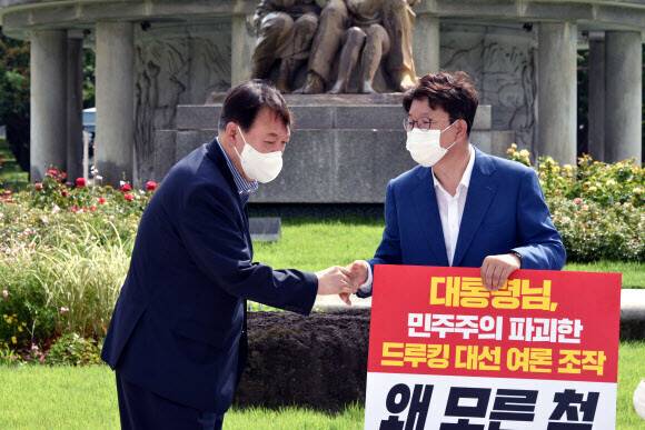 윤석열 전 검찰총장이 지난 8월 청와대 앞 분수대 앞에서 드루킹 대선 여론조작에 대한 문재인 대통령의 사과 촉구 1인시위를 하는 권성동 의원을 방문해 악수하고 있다. 공동취재사진