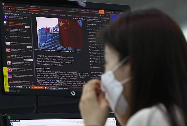 An employee reads an article on China’s Evergrande debt crisis at Hana Bank’s dealing room in Seoul on Thursday. South Korean authorities said they have been monitoring risks stemming from Evergrande’s intense liquidity crisis as Beijing tightened regulations in its property sector to rein in excessive debt and speculation in recent months. (Yonhap)