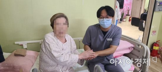 무연고 환자 A씨와 황명환 보건의료정보관리사가 지난달 31일 경기도 의정부 카네이션 요양병원 내 병상 침대에 앉아 함께 웃어보이고 있다.