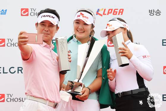 Ryu Hae-ran, center, celebrates their pro-am team trophies with Kim Ji-yeong, right, and singer Im Chang-jung at the Elcru-TV Chosun Pro Celebrity 2021 tournament trophy at Island Country Club in Ansan, Gyeonggi on Sunday. [KLPGA]