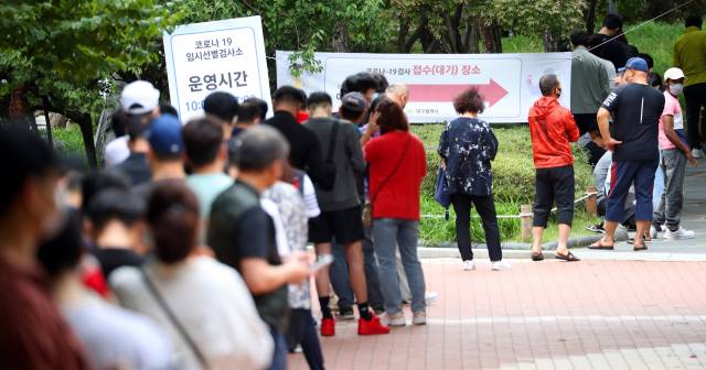 전국적으로 코로나19 증가세가 매서운 가운데 휴일인 26일 오후 2시 30분께 대구 중구 국채보상공원에 마련된 임시선별검사소에서 시민들이 검사를 받기 위해 길게 줄지어 기다리고 있다./연합뉴스
