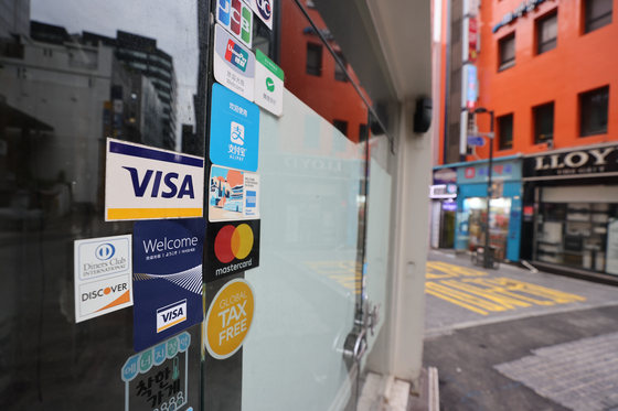 Credit card logo on a store that has been closed in Myeong-dong, Seoul on Monday. The government said a cash-back program whose goal is to help small stores that have been affected by the social distancing regulation will start Oct. 1. [YONHAP]