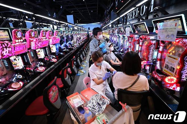14일(현지시간) 일본 오사카의 파친코 아케이드에서 주민이 코로나19 백신을 접종 받고 있다. © AFP=뉴스1 © News1 우동명 기자