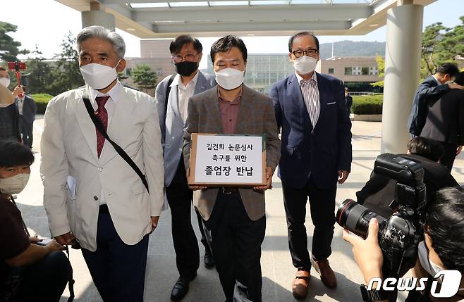 윤석열 전 검찰총장 부인 김건희씨의 박사학위 논문 '본조사 불가' 입장에 항의하는 국민대 동문들이 1일 오전 서울 성북구 국민대 본관 앞에서 뜻을 함께 하는 200여 명의 졸업장을 반납하고 있다. 국민대 연구윤리위는 부정행위 의혹을 받는 김씨의 테크노디자인전문대학 박사학위 논문 '아바타를 이용한 운세 콘텐츠 개발 연구: 애니타 개발과 시장적용을 중심으로' 등 2007~2008년 작성 논문 3건에 대해 예비조사를 실시했으나 '시효만료'를 이유로 검증이 불가능하다고 결론 내렸다. 2021.10.1/뉴스1 © News1 오대일 기자