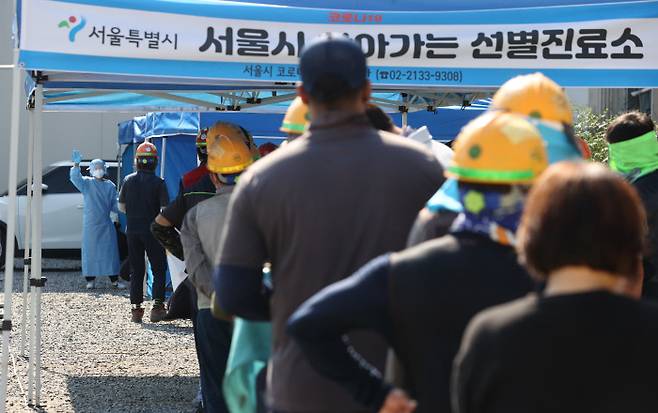 24일 오전 서울 강남구의 한 건설 현장에 마련된 ‘서울시 찾아가는 선별진료소’에서 작업자들이 코로나19 검사를 받기 위해 줄을 서 있다. 연합뉴스
