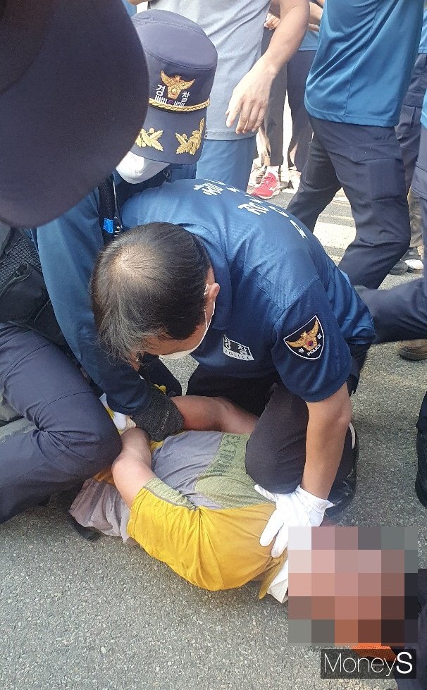 지난달 30일 오후 합천군청 광장에서 경찰이 공무원들을 향해 '돼지분뇨'를 투척한 주민을 체포하고 있다./사진=반대투쟁위원회 제공.
