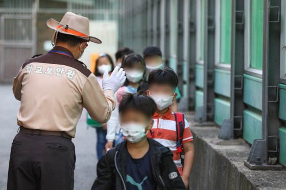 지난달 6일 서울 성북구의 한 초등학교에서 학생들이 체온 검사를 위해 한 줄로 서서 등교하고 있는 모습. 연합뉴스