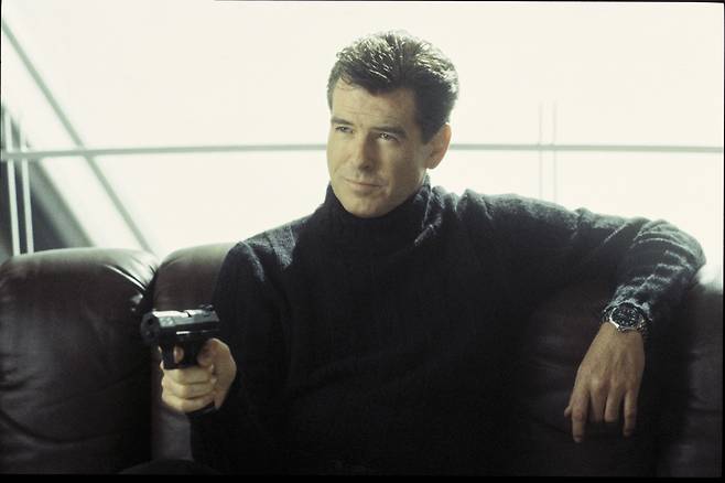 제임스 본드역으로 분한 피어스 브로스넌이 본드워치를 차고 총을 겨누고 있는 모습.