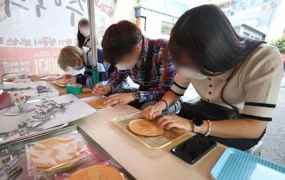 지난 1일 오후 서울 종로구 대학로의 한 가게에서 시민들이 달고나 뽑기를 하고 있다.  뉴스1