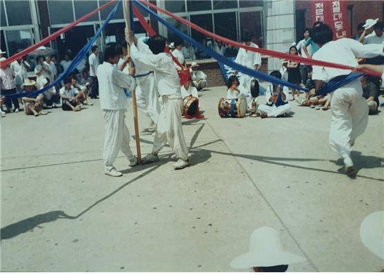 ▲88년 7월 농활공연 ‘못내 못내 절대 못내!’ 사진 1- ‘부당수세 철폐’ 현수막이 뒤로 보이는 가운데 신태인역 광장에서 농민들이 문선대 공연을 보고 있다. 한마음으로 단합하여 보자는 의미로 ‘단심줄 엮기’를 차용하였다. ⓒ마승락