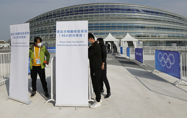 2022 겨울 올림픽 테스트 이벤트 대회가 열린 중국 수도 베이징의 빙상 경기장 앞에서 지난 8일 대회 관계자들이 48시간 안에 받은 코로나19 핵산검사 결과를 제시하라는 문구가 적힌 안내판을 설치하고 있다. 베이징/로이터 연합뉴스
