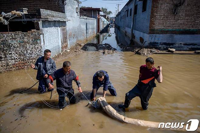 (진중 AFP=뉴스1) 금준혁 기자 = 11일(현지시간) 중국 산시성에 쏟아진 집중호우로 인해 홍수가 발생해 구조대원들이 도시에서 물을 빼내고 있다.  (C) AFP=뉴스1