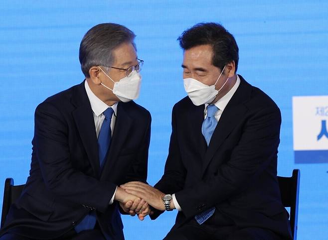 Lee Nak-yon congratulates Lee Jae-myung, who was chosen as the Democratic Party’s candidate for president, during a joint speech session in Seoul on Sunday. (Yonhap News)