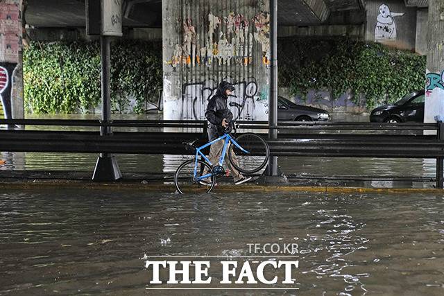 깊은 물 속에서 자전거 운반하는 시민. / 아테네=AP.뉴시스