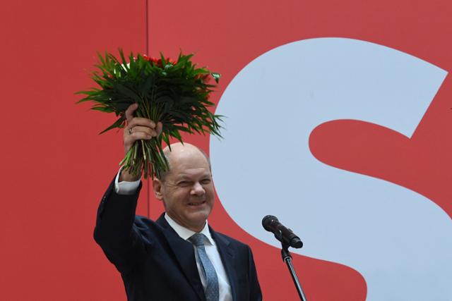 지난달 26일 독일 연방의원 선거에서 1위를 차치한 올라프 숄츠 독일 사민당 대표가 27일 베를린 당사에서 성명을 발표한 후 꽃다발을 흔들며 웃고 있다. 베를린=AP 뉴시스