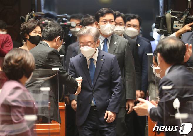 더불어민주당 대선 후보인 이재명 경기도지사가 15일 오전 서울 국회에서 열린 더불어민주당 의원총회에 축하 인사를 받으며 입장하고 있다. 2021.10.15/뉴스1 © News1 이동해 기자