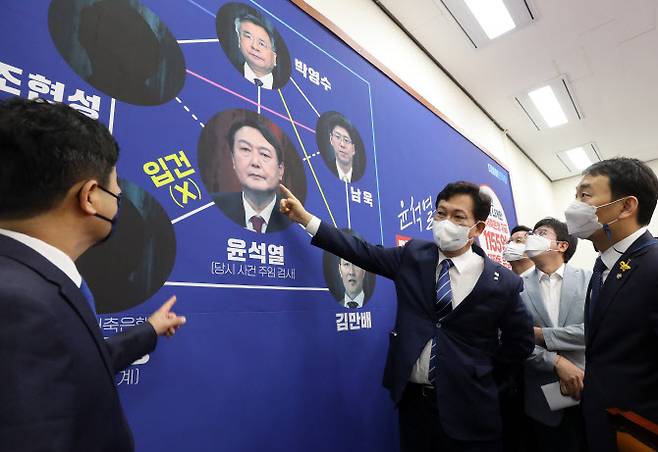 더불어민주당 송영길 대표와 최고위원들이 18일 오전 국회에서 열린 최고위원회의에 앞서 대장동 개발 의혹 관련, 부산저축은행 수사를 지적하는 내용이 담긴 배경판을 바라보며 대화를 나누고 있다. (사진= 국회사진기자단)