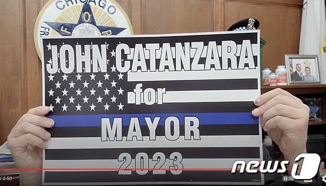 존 카탄자라 시카고 경찰노조(FOP) 위원장은 시 당국의 '백신 접종 의무화' 명령에 불복하라는 공개성명을 금지한다는 법원 판단에도 자기 주장을 굽히지 않고 있다. 사진은 법원 판결 직후 그가 유투브에 짧은 동영상과 함께 올린 '존 카탄자라를 2023년 시장으로'라고 쓴 푯말. © News1