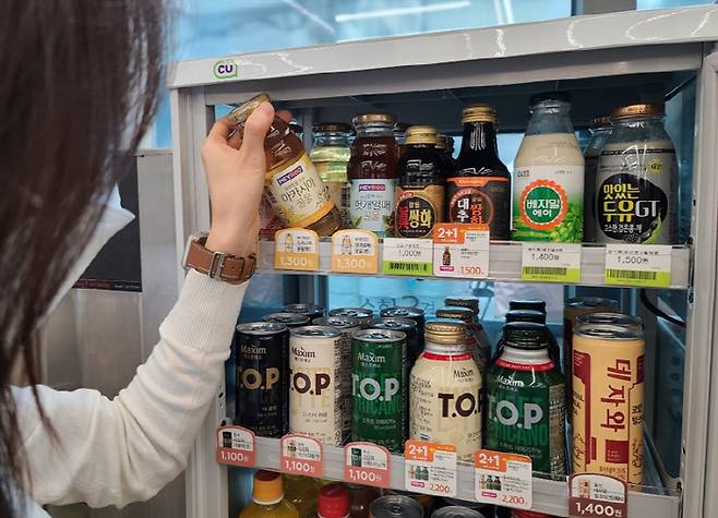 편의점 CU 내 온장고 코너에서 음료를 소비자가 고르고 있다 [사진 제공 = CU]