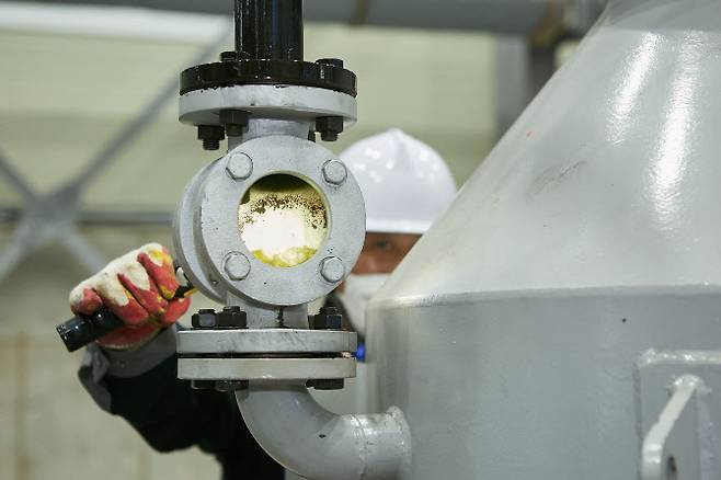 인천 서구 뉴에코원 공장에서 한 엔지니어가 시험 가동되는 열분해유 생산 설비에서 열분해유를 확인하고 있다. (사진=SK지오센트릭)