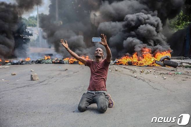 18일(현지시간) 아이티에서 미국인 선교단 17명이 납치되는 사건이 발생하자 수도 포르토프랭스에서 치안 불안에 항의하는 파업이 벌어졌다. 사진은 한 남성이 불타고 있는 타이어 앞에 무릎을 꿇고 앉아 있는 모습. © AFP=뉴스1 © News1 신윤하 기자
