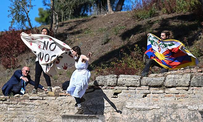 고대 올림픽 발상지인 그리스 올림피아에서 18일(현지시간) '2022 베이징 동계올림픽' 성화 채화식이 열리는 동안 인권운동가들이 티베트 국기와 현수막을 펼치며 기습시위를 벌이자 사복경찰이 저지하고 있다. 올림피아=AFP연합뉴스
