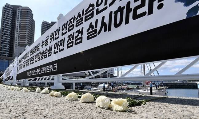지난 14일 전남 여수시 웅천동 이순신마리나 요트정박장 주변 울타리에 잠수 작업 중 숨진 특성화고 실습생 고(故) 홍정운 군을 추모하는 현수막이 걸리고 조화가 놓여져 있다. 뉴시스