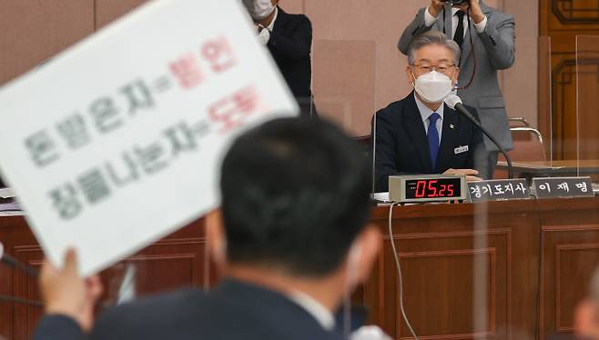 더불어민주당 대선 후보인 이재명 경기지사가 20일 수원 경기도청에서 열린 국회 국토교통위원회 국정감사에서 대장동 의혹과 관련한 내용이 담긴 손팻말을 들고 질의하는 박성민 국민의힘 의원을 바라보고 있다. 국회사진기자단