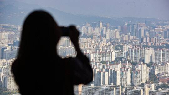 한 시민이 서울 영등포구 63스퀘어에서 아파트 밀집 지역을 촬영하고 있다. <연합뉴스>