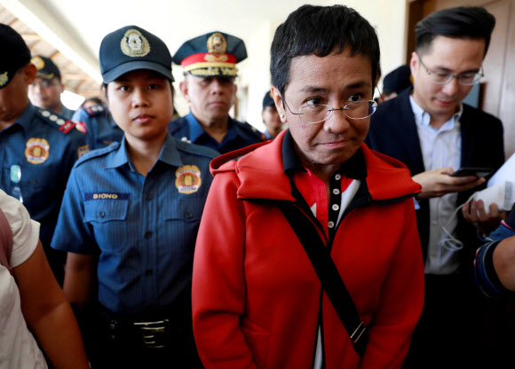 필리핀 온라인 탐사보도 매체 래플러의 공동설립자이자 최고경영자(CEO)인 언론인 마리아 레사가 2019년 3월 체포됐다가 보석으로 석방되며 경찰에 둘러싸인 모습. 로이터 연합뉴스