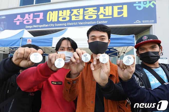국내 코로나19 백신 접종 완료율이 70%를 돌파한 가운데 휴일인 24일 오전 대구육상진흥센터에 마련된 수성구예방접종센터에서 백신 접종을 마친 외국인 근로자들이 질병관리청과 대구시가 무료로 배포하는 '고마워 백신' 배지를 들어 보이고 있다. 2021.10.24/뉴스1 © News1 공정식 기자