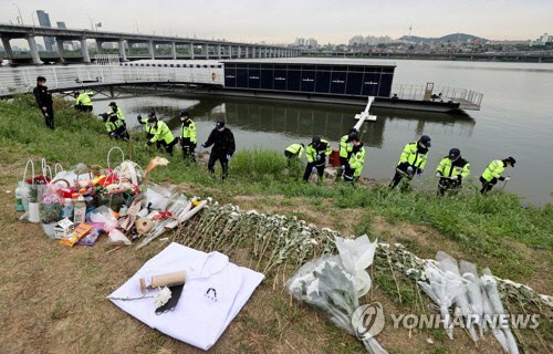 지난 5월 10일 경찰이 한강공원에서 실종됐다가 숨진채 발견된 의대생 손정민 씨 친구의 휴대폰을 수색 중인 가운데 서울 반포한강공원 수상택시 승강장 인근에 손씨를 추모하는 꽃다발과 의사 가운이 놓여 있다. <연합뉴스>