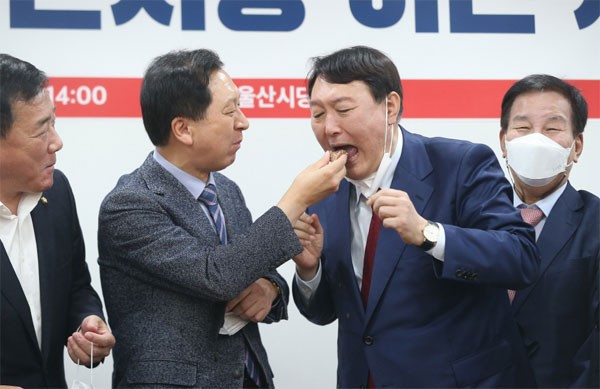 국민의힘 대선 경선 주자인 윤석열 전 검찰총장(왼쪽 셋째)이 23일 오후 울산시당 이전 개소식에 참석해 울산을 지역구로 두고 있는 김기현 국민의힘 원내대표(왼쪽 둘째)에게 떡을 받아 먹고 있다. [사진 출처 = 연합뉴스]