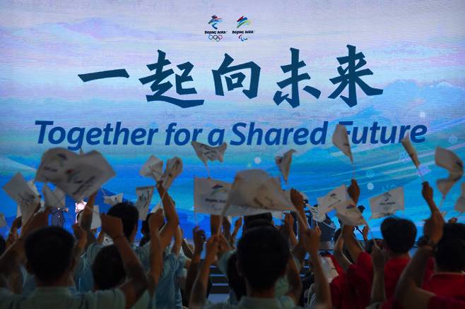 지난 17일 베이징에서 열린 2022 베이징 동계올림픽 및 장애인올림픽 구호인 ‘함께 공유된 미래로’(Together for a Shared Future)가 발표되자 참가자들이 환호하고 있다. (사진=뉴시스)