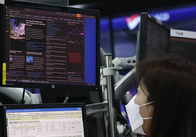 23일 오전 명동 하나은행 본점 딜링룸에서 한 직원이 미국 연방준비제도(Fed)의 자산매입 축소(테이퍼링)와 관련한 기사를 살펴보고 있다./연합뉴스