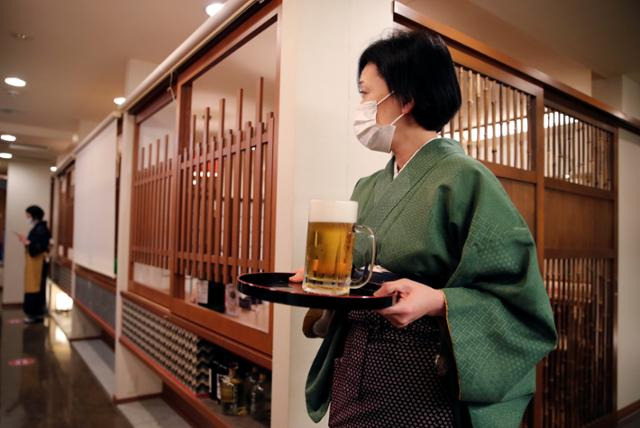 일본 전역에서 긴급사태 선언이 해제된 1일, 음식점에서 주류 판매가 허용되자 도쿄의 한 음식점에서 종업원이 맥주를 나르고 있다. 25일부터는 도쿄와 수도권 3현에서 영업시간 제한도 해제됐다. 도쿄=로이터 연합뉴스