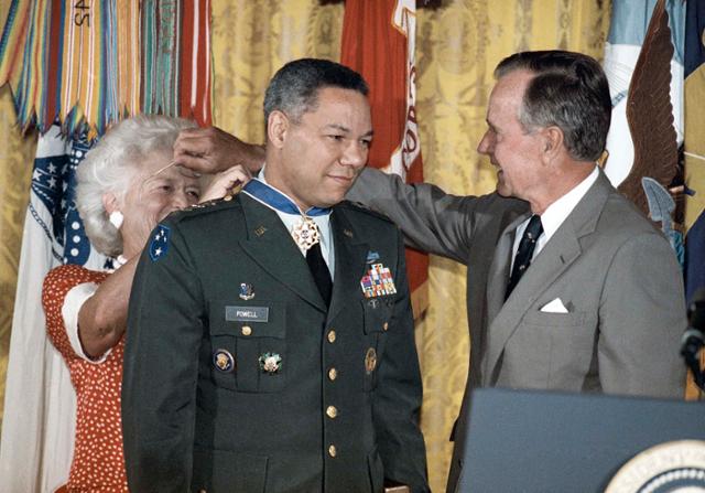 1991년 7월 3일 조지 부시 미국 대통령은 백악관에서 합참의장인 콜린 파월 장군에게 자유의 메달을 수여하는 영부인 바바라 부시에게 안경을 빌려주고 있다. AP 연합뉴스