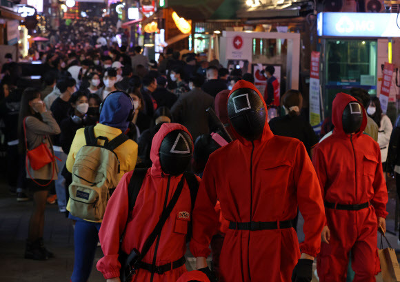 주말 핼러윈을 앞둔 29일 오후 인파가 몰린 서울 용산구 이태원 세계음식거리에서 넷플릭스 오리지널 시리즈 ‘오징어 게임’의 등장 인물 복장을 한 시민들이 기념촬영을 하고 있다. 2021.10.29 연합뉴스