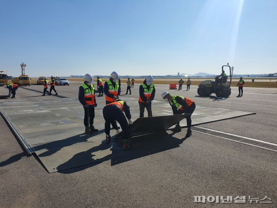 지난 28일 오후 인천공항에서 진행된 인천공항 활주로 긴급복구 훈련에서 폭파구복구팀이 활주로에 대형 폭파구가 생긴 상황을 가정해 비상활주로를 확보하고 비상용등화를 설치하는 훈련을 진행하고 있다. 사진=인천국제공항공사 제공。