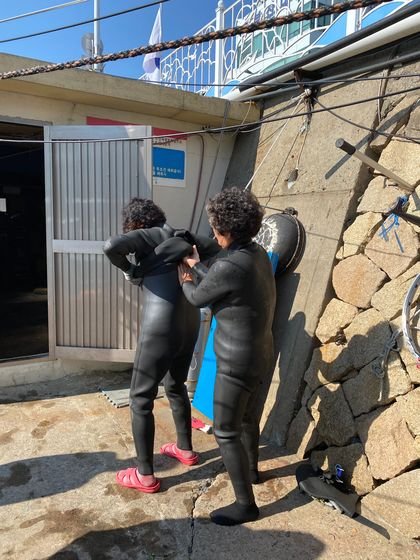 부산 남천어촌계 해녀들이 서로 도와가며 해녀복을 입고 있다. 사진 동의대 한일해녀연구소