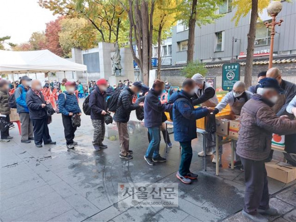 서울 종로구 탑골공원에서 2일 노인들이 무료로 지급되는 도시락을 미리 받아 놓았던 검은색 비닐봉지에 받고 있다. 탑골공원 정문인 삼일문 앞에서 진행된 무료 급식은 30분도 안 돼 종료됐다.오세진 기자 5sjin@seoul.co.kr