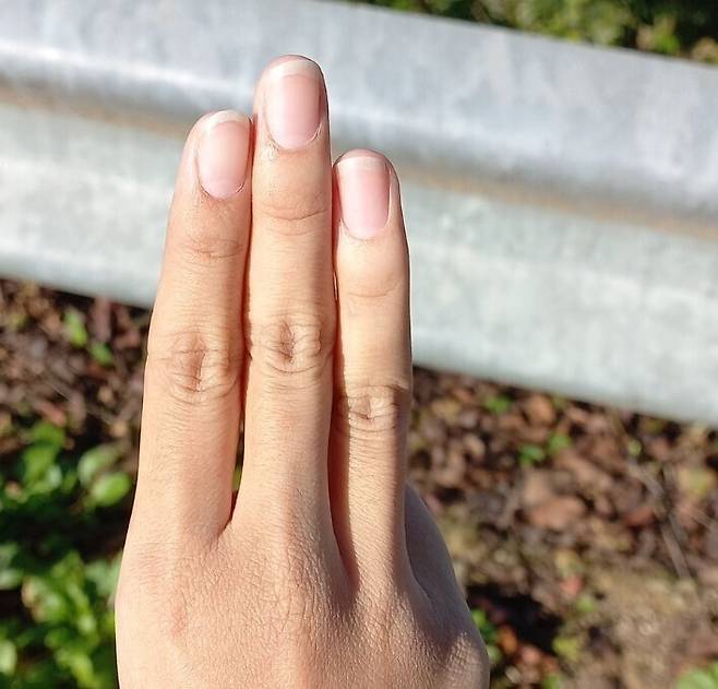 Kaing (pseudonym), a young person from Myanmar, holds up the three-finger salute.