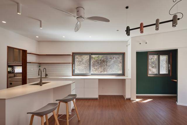 집의 중심인 1층 주방과 응접실. 정면에 보이는 창 너머가 법화산 자락으로, 가끔씩 고라니가 와서 놀다 간다. 오른쪽 녹색 벽지로 마감한 공간이 아내의 '비밀의 방'이다. 노경 건축사진작가 제공