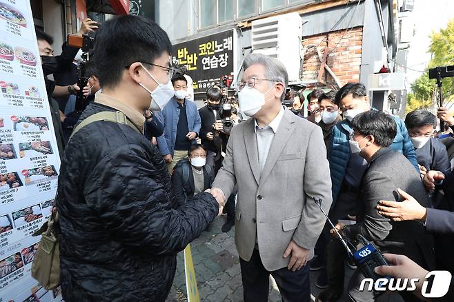 이재명 더불어민주당 대선 후보가 5일 오전 대구 북구 경북대학교 인근에 도착해 첫 일정으로 예정된 '대구 청년 명수씨와 식사'를 앞두고 음식점 앞에서 '나도 대통령 친구가 있었으면 좋겠다'라는 피켓을 들고 마중 나온 백명수씨와 인사 나누고 있다. 2021.11.5/뉴스1 © News1 공정식 기자